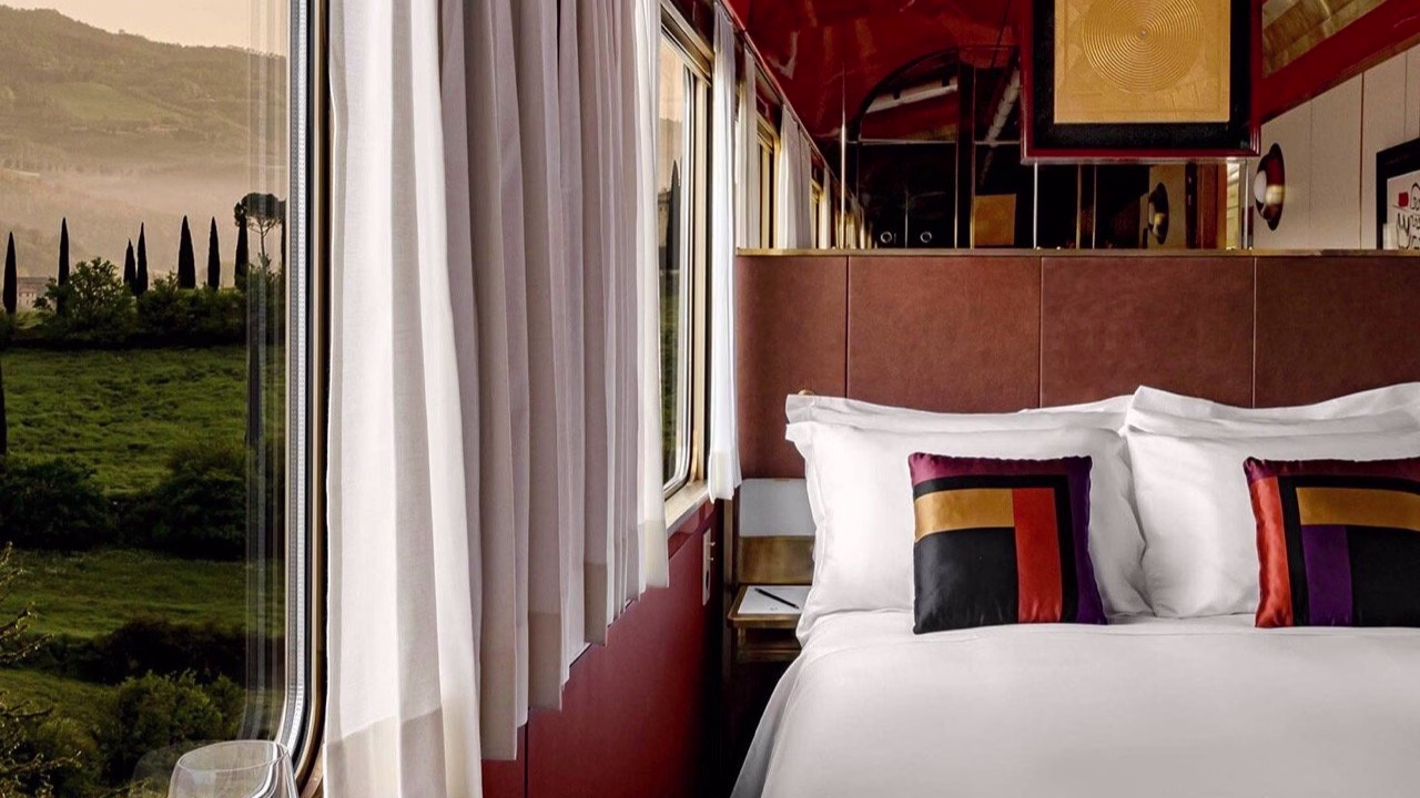 A luxurious hotel-style bed positioned next to a large train window.