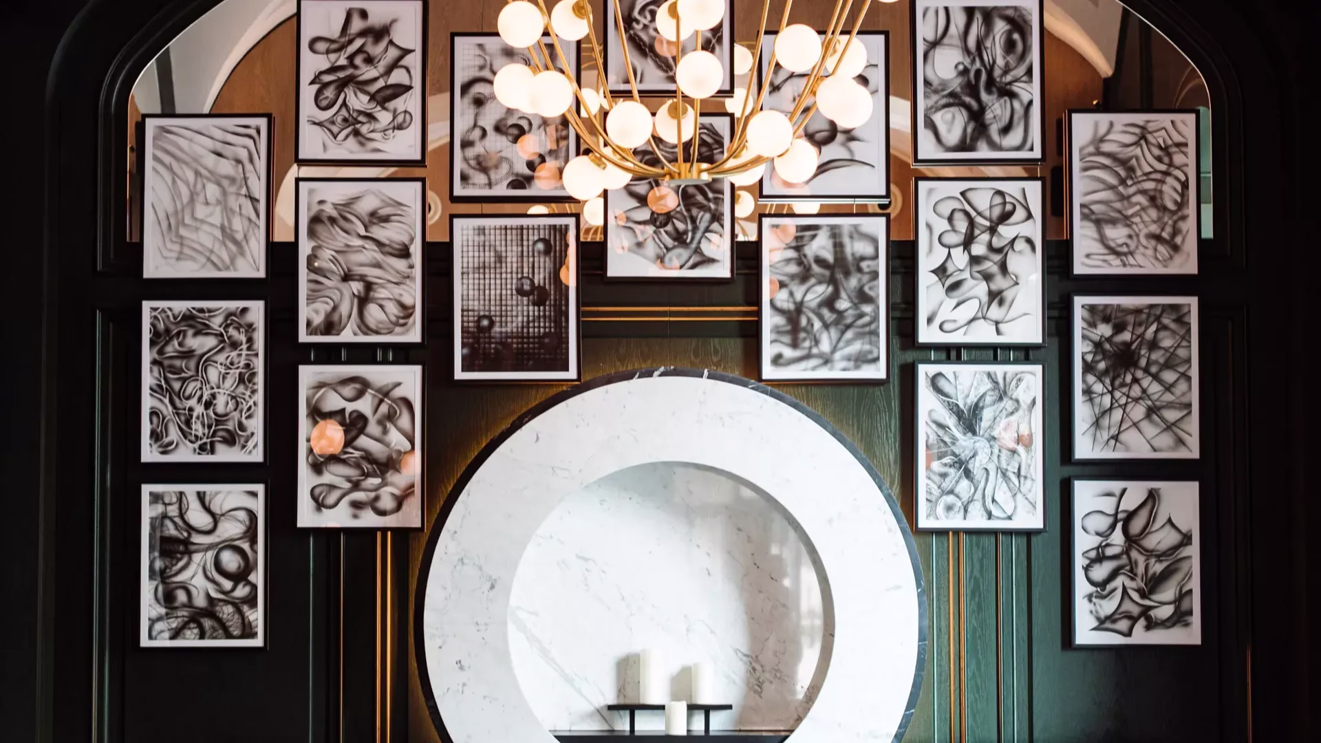 A collection of art paintings elegantly displayed on a green wall.